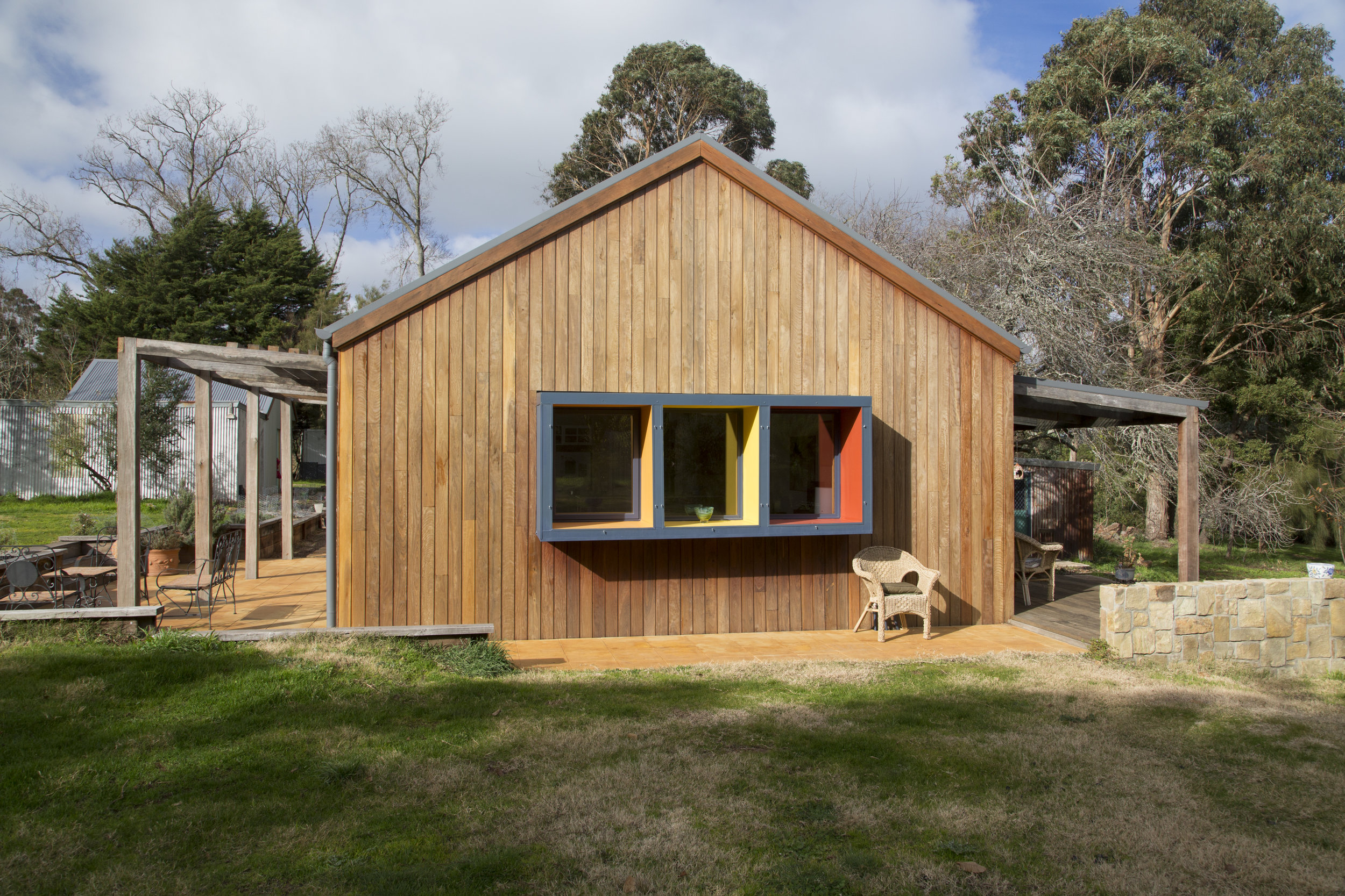 A modern home exterior with bold, bight window frames and stained wood facade designed by Enduring Domain Architecture